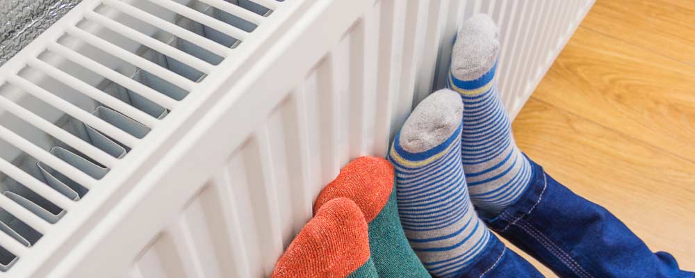 Four feet in two pairs of colourful wool socks pressed against a warm radiator