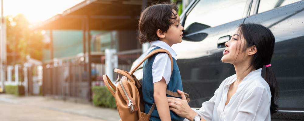 A young mom and her small kid get ready for school beside the family car