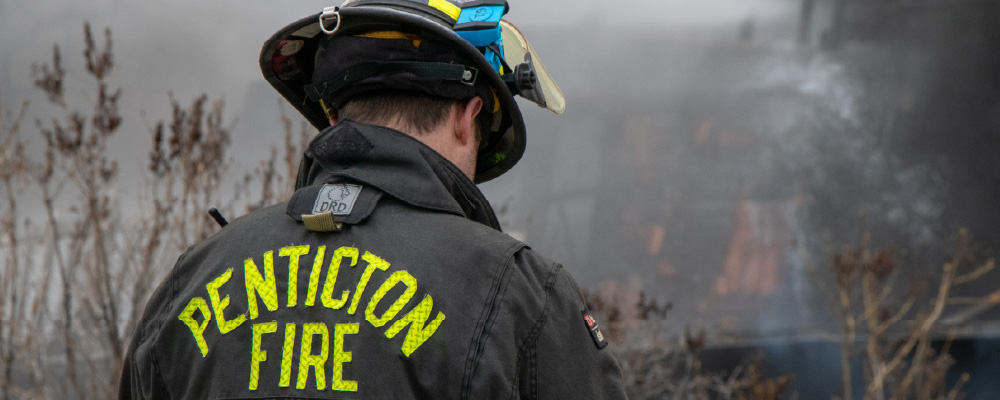 A Penticton Firefighter is seen from behind after helping extinguish a house fire.