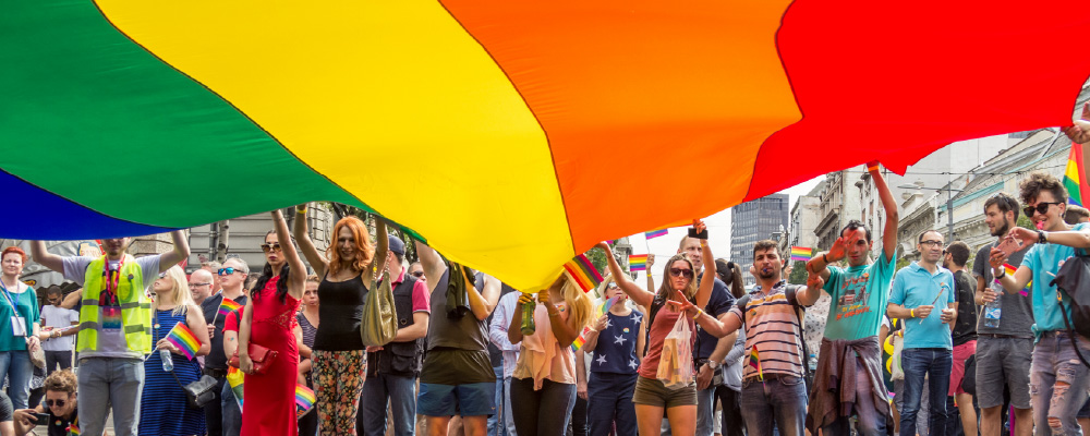 Pride Parade participants wave a giant rainbow flag in the air