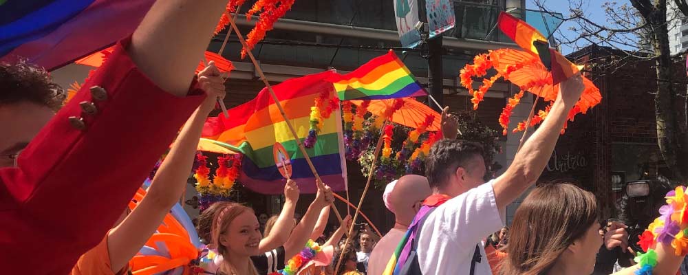 BC NDP supporters waving flags in the pride parade