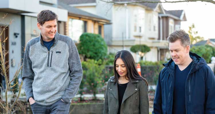 Premier David Eby walks down a sidewalk talking to a young couple