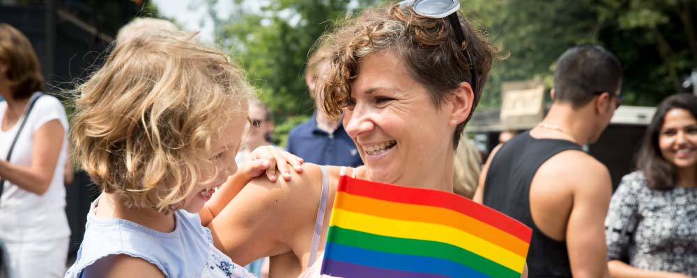 A mom and her daughter wave a pride flag