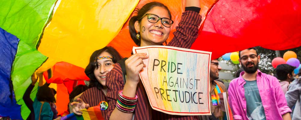 A woman at a rally holds a sign that says 'pride over prejudice'