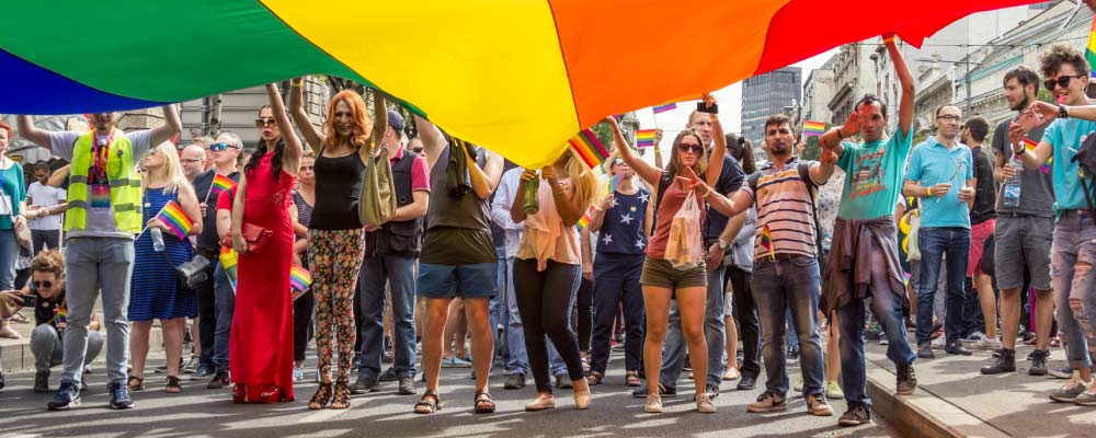 People attending a pride parade wave a giant flag